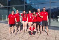 VSC-Team mit Medaillen  vor dem Bad mit Trainer und Betreuern